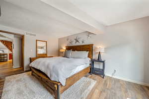 Bedroom with visible vents, baseboards, and wood finished floors