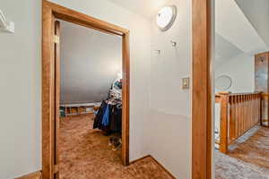 Hallway with vaulted ceiling and carpet flooring