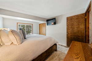 Bedroom with a textured ceiling, baseboards, and wood finished floors