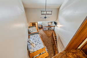 Staircase featuring a ceiling fan, carpet, and a high ceiling