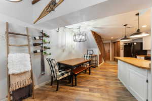 Dining space featuring light wood finished floors, baseboards, an inviting chandelier, stairs, and recessed lighting