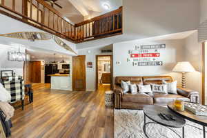 Living room with a notable chandelier, visible vents, a high ceiling, wood finished floors, and baseboards