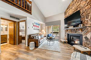 Living area with visible vents, a fireplace, a high ceiling, and wood finished floors