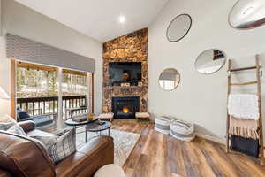 Living area with high vaulted ceiling, a fireplace, baseboards, and wood finished floors