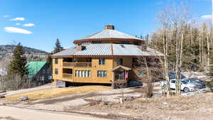 Exterior space with a balcony, a chimney, and metal roof