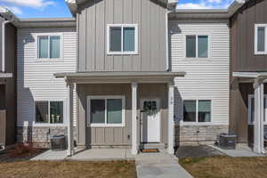 Townhome / multi-family property featuring stone siding, central AC unit, and board and batten siding