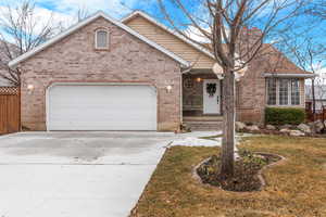 Ranch-style home featuring brick siding, a front yard, fence, a garage, and driveway