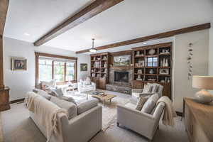 Living room with light colored carpet, beamed ceiling, a textured ceiling, a fireplace, and recessed lighting