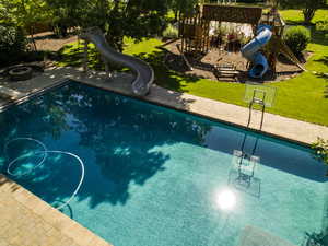 Pool featuring a playground, a lawn, and a water slide