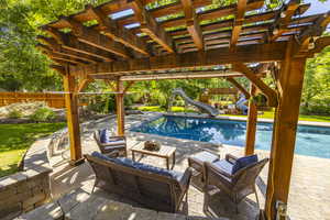 View of pool featuring a water slide, fence, a fenced in pool, a pergola, and a patio area