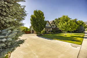 Tudor-style house featuring driveway, metal roof, a standing seam roof, fence, and a front lawn