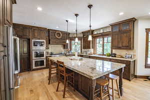 Kitchen featuring stainless steel appliances, light wood finished floors, a breakfast bar area, and tasteful backsplash