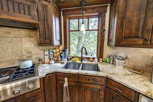 Kitchen featuring a healthy amount of sunlight, a sink, light stone countertops, and stainless steel gas stovetop