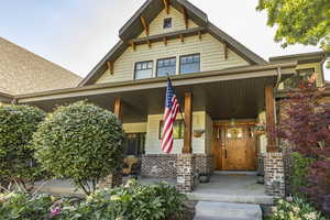 View of exterior entry featuring a porch and brick siding