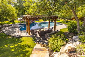 Outdoor pool featuring a fire pit, a yard, and a patio area