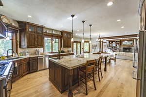 Kitchen featuring appliances with stainless steel finishes, an island with sink, light wood-type flooring, and a sink