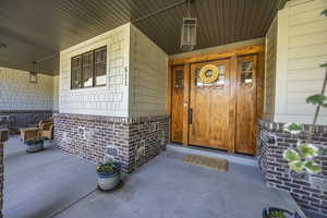 Property entrance featuring a porch and brick siding