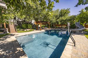 View of swimming pool featuring a water slide, fence, stairway, a pergola, and a patio area