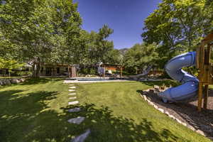 View of yard with a pergola, an outdoor pool, and a playground