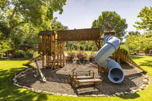 View of playground featuring a yard and fence