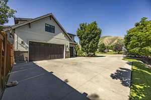 View of side of property with brick siding, a mountain view, driveway, and an attached garage