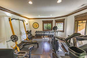 Workout area featuring visible vents, dark wood-style floors, ornamental molding, a textured ceiling, and recessed lighting