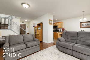 Living room featuring dark wood-type flooring, stairway, and inviting chandelier