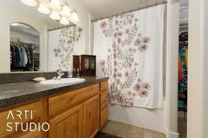 Bathroom with a walk in closet, vanity, and tile patterned floors