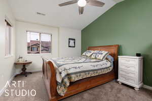 Carpeted bedroom featuring baseboards, visible vents, vaulted ceiling, and a ceiling fan