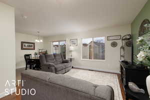 Living area featuring a healthy amount of sunlight, dark wood finished floors, baseboards, and an inviting chandelier