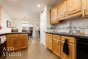 Kitchen with light tile patterned floors, backsplash, dark countertops, and a sink