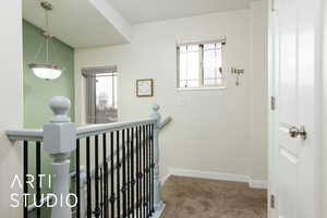 Corridor featuring carpet floors, a wealth of natural light, an upstairs landing, and baseboards