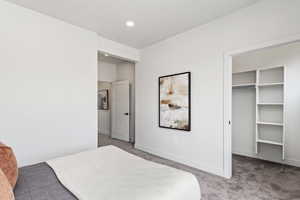 Bedroom with a spacious closet, recessed lighting, carpet flooring, and baseboards