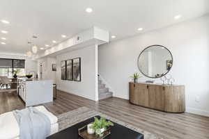 Living area with baseboards, stairway, wood finished floors, and recessed lighting