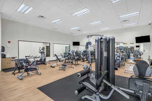 Workout area featuring visible vents, a towering ceiling, a drop ceiling, and wood finished floors