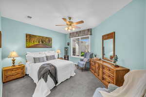 Carpeted bedroom featuring visible vents and a ceiling fan