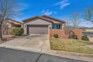 View of front facade featuring an attached garage, fence, a tile roof, concrete driveway, and stucco siding