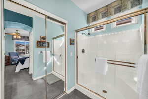 Bathroom featuring ensuite bathroom, a shower stall, and baseboards