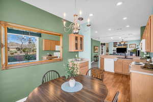 Dining area with light wood-type flooring, ceiling fan with notable chandelier, and recessed lighting