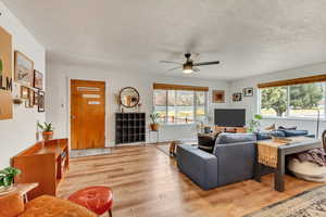 Living area with a healthy amount of sunlight, light wood-style floors, and ceiling fan.