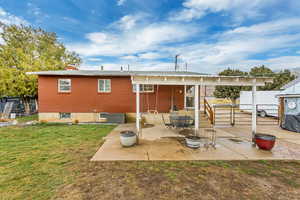 Back of house featuring brick siding, a yard, a chimney, a patio area, and fence