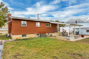 Back of property featuring central AC unit, a chimney, a yard, a patio area, and brick exterior.