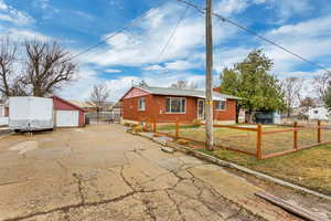 View of front of house featuring an outbuilding, brick siding, a fenced front yard, and a front yard