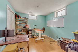 Office with visible vents, a textured ceiling, baseboards, and wood finished floors