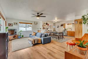 Living room with a ceiling fan, light wood-style flooring.