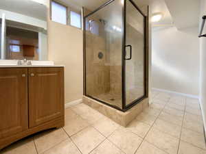 Bathroom with a stall shower, vanity, baseboards, and tile patterned floors