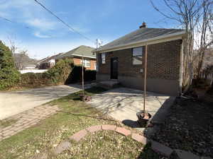 Rear view of house with a chimney, a patio, and brick siding