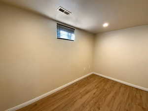 Below grade area with recessed lighting, visible vents, baseboards, and wood finished floors