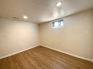 Basement with visible vents, baseboards, and wood finished floors