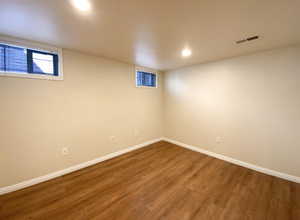 Basement featuring wood finished floors, visible vents, and baseboards